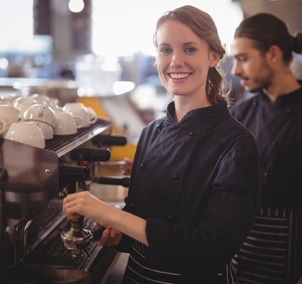 Young woman in a cafe operating a coffee machine