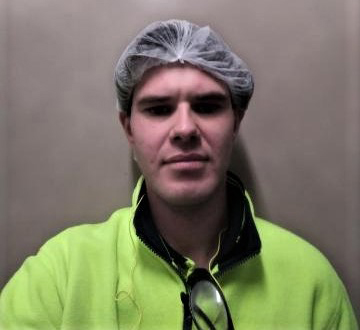 Man wearing high vis shirt with a hair net looking at camera