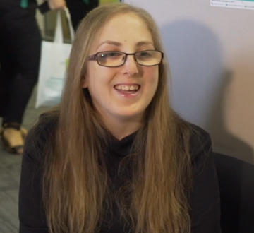 Young girl with glasses smiling at someone out of view