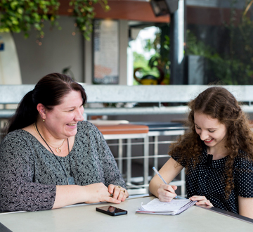 Two women sitting at a table talking and smiling