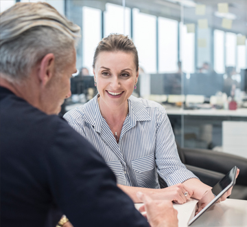 A woman looking and smiling at a man while holding a tablet