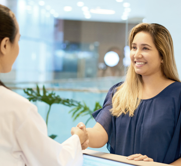 A woman smiling and shaking hands with a doctor