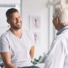 A man sitting on a bed and talking to a doctor