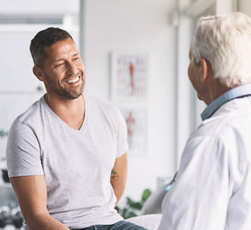 A man sitting on a bed and talking to a doctor