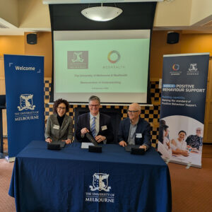 Three people sitting at a table signing an agreement. They have folders with the agreement in them in front of them and they are smiling. The people are Professor Jennifer Balint, Dean, Faculty of Arts; Tim Morphy, CEO, MedHealth; and Mike McGukin, Dean, Medical, Dentistry and Health Sciences.